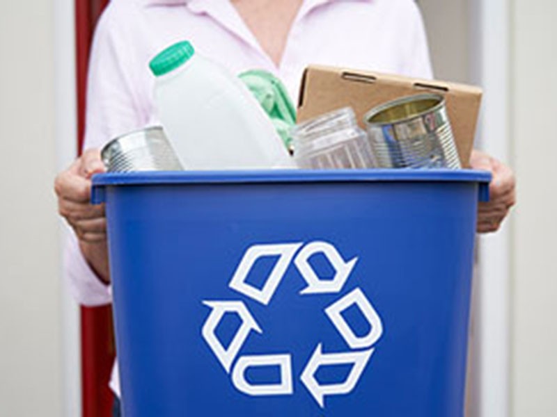 Person holding a recycling bin, representing garbage and recycling services